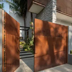 The entrance to the Siri residence is revealed behind massive corten steel gates, hinting at the tropical sanctuary and unique architectural drama that lies within.