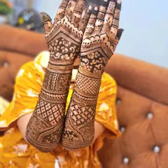 A classic bridal pose showing off the symmetry and detail of the mehndi on both hands. This design incorporates heavy jaal work on the arms and floral patterns on the palms.