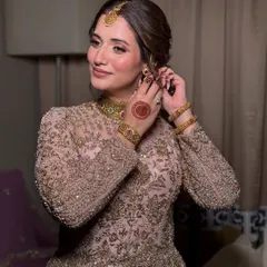 A candid getting-ready shot. The soft, romantic updo and the placement of her jewelry are key details that complete the traditional Nikkah look.