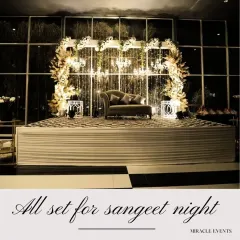 This elegant sangeet stage is designed with a backdrop of cascading lights and lush white florals, creating a sophisticated focal point for the evening's festivities.