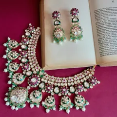 This complete Kundan necklace and earring set is a perfect statement piece to elevate any ethnic outfit. The combination of green, red, and white stones is a classic.