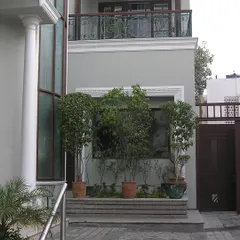 This home features an asymmetrical entrance that is centered yet unconventional. A recessed foyer with a warm solid wood door opens into a long, open corridor, establishing a journey through the space.