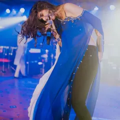 A high-energy shot of singer Kinjal Dave during a live performance. She's wearing a custom oxidized silver jewellery set that moves with her on stage.