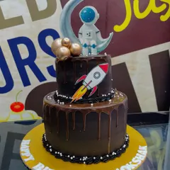 A 3.5kg two-tiered chocolate drip cake with a space theme, topped with a fondant astronaut and rocket ship.