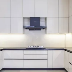 This U-shaped kitchen uses high-gloss white handleless cabinets to create a brilliantly reflective and spacious feel. The black countertop provides a sharp, modern contrast, grounding the design.