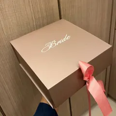 A simple yet elegant gift box for the bride. The rose gold box is customized with 'Bride' in a beautiful script and tied with a satin ribbon, ready to be filled with thoughtful goodies for her new journey.