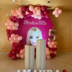 The main stage for the "Five is a Vibe" Barbie party, showing the custom backdrop, balloon garland, and fluted plinths for the cake.