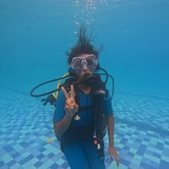 A participant flashes a peace sign, clearly enjoying her introduction to the world of scuba diving in a safe pool environment.