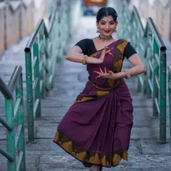 A graceful pose captured during a photoshoot at a temple. The setting provides a serene and powerful backdrop that complements the traditional aesthetics of Bharatanatyam.