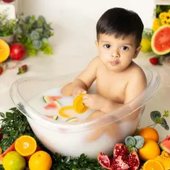 A healthy and fun fruit bath! This little one is surrounded by a colorful array of fresh fruits like oranges and watermelon, making for a unique and vibrant summer-themed shoot.