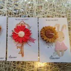 A collection of my floral wax sachets. Here you can see a red gerbera design on a key-themed card and a sunflower design on a rabbit-themed card, showing the creative combinations available.