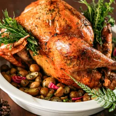 A classic Christmas centerpiece: a whole roasted turkey, glistening and golden-brown. We brine and roast our turkeys to perfection, serving them with all the traditional trimmings for a memorable holiday feast.