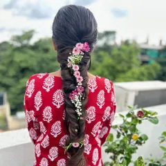 A beautiful fishtail braid adorned with a delicate trail of pink and white flowers, creating a whimsical and romantic look.