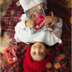 Cozying up with a Christmas story. This shot from a holiday mini session captures the magic of the season, with a festive red hat and a special letter to Santa, all surrounded by twinkling lights.