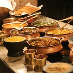 For my wedding catering services, I use traditional copper and stone serving bowls to enhance the buffet's presentation. This spread features a variety of rich Punjabi and North Indian vegetarian curries, ready for a large wedding reception.