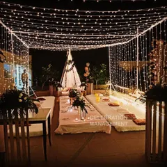 I can turn any terrace into a magical setting for a birthday dinner. This setup features a canopy of fairy lights creating a starry sky effect, with low seating on mattresses and cushions for a cozy, intimate gathering with friends and family.