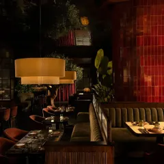The interplay of textures and reflections. A column of glossy red ceramic tiles punctuates the space, while the mirrored ceiling and fluted wood panels add layers of visual complexity.