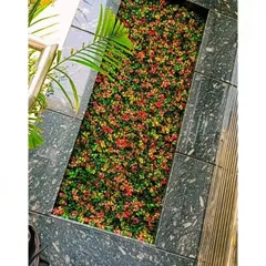 An overhead shot of the completed floor inlay. The mix of red, yellow, and green artificial ground cover creates a colorful, textured strip that contrasts beautifully with the dark marble tiles.