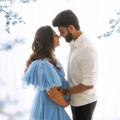 A soft and dreamy maternity portrait. The flowing blue gown and delicate floral accents create a serene and romantic atmosphere for the expecting couple.