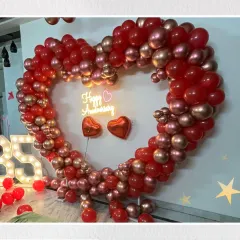 Celebrating a love that lasts a lifetime. This grand heart-shaped balloon arch, made with rich red and shimmering rose gold balloons, creates the perfect romantic photo opportunity for a very special anniversary.
