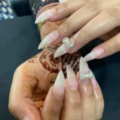 A closer look at the details on these festive stiletto nails. The intricate rhinestone bows and sparkling glitter finish make this a truly standout design, especially when paired with henna for a celebration.
