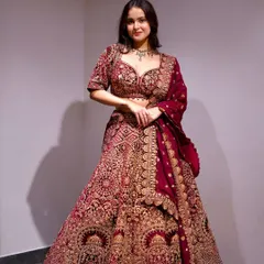 A stunning bridal lehenga in a deep maroon velvet, covered in luxurious hand-embellished details. This piece is pure opulence, perfect for a grand wedding ceremony.