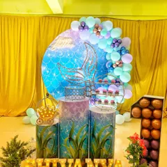 An enchanting mermaid themed birthday decoration. The setup features a sparkling mermaid tail backdrop, under-the-sea themed pedestals, and the birthday girl's name in marquee letters.