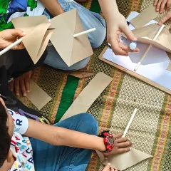 Children work together to create paper pinwheels during a craft session. This simple toy is not only fun to make but also teaches a basic principle of how wind works, blending art with science.