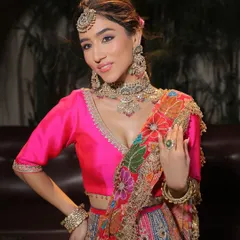 A portrait of a bride ready for her Mehendi. The makeup is fresh and vibrant, with a bright pink lip that beautifully contrasts with her multi-coloured lehenga.