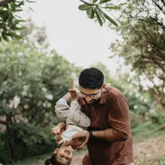 A father playfully holds his daughter upside down during their outdoor session, capturing a moment of pure fun and trust.