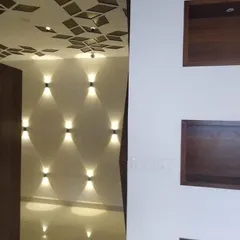 This image shows our expertise in creating dramatic lighting effects. The textured wall with up-and-down sconces and the geometric false ceiling with recessed lights work together to create a sophisticated ambiance.
