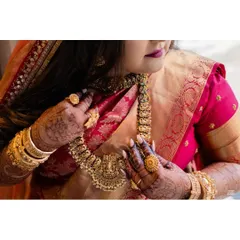 A detail shot of the bride's jewelry. The layered gold necklaces and statement rings are characteristic of a traditional Mallu bride, adding richness and grandeur to her look.