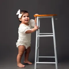 This little girl is just starting to stand, and this simple studio portrait captures that exciting milestone perfectly against a solid grey backdrop.