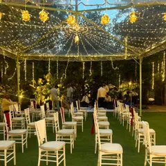 An intimate seating arrangement under a clear-top tent with golden fairy lights, perfect for an elegant evening reception.