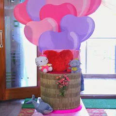A whimsical prop featuring cartoon heart balloons and cute stuffed animals like Hello Kitty. This kind of custom piece can be a fun addition to a child's birthday party or a valentine's themed event.