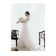 A full-length portrait of the Christian bride in her flowing white gown, holding a bouquet of white roses, the picture of elegance.