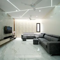 This living room design for a villa features dramatic geometric ceiling lights, a textured accent wall, and a comfortable quilted sectional sofa, all contributing to a modern and sophisticated ambiance.