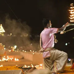 A priest performs the Ganga Aarti ritual at Dashashwamedh Ghat. This wide shot shows the synchronized movements and the diyas lighting up the steps of the ghat.
