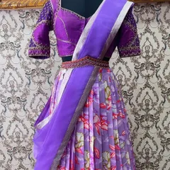 A trendy lavender floral half saree. The pleated skirt is paired with a handcrafted maggam work blouse and a pure organza dupatta for a fresh, contemporary look.