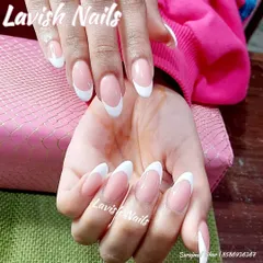This image highlights the crisp white tips and sheer pink base of a classic French manicure on long, elegant almond nails.