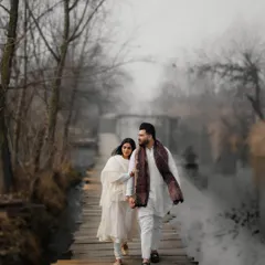 Walking hand-in-hand across a rustic wooden bridge in Kashmir. The misty, atmospheric setting creates a beautifully romantic and timeless feel for this pre-wedding portrait, highlighting the couple's journey together.
