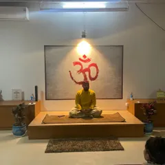 As a guru, I hold the space for my students to go deep into their meditation. Here, I am guiding a session from the front of the class, with the sacred symbol of Om behind me to amplify the energy.