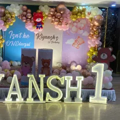 The main stage for 'Kiyansh's' first birthday, featuring marquee letters spelling his name and the number '1', set against a teddy bear backdrop.