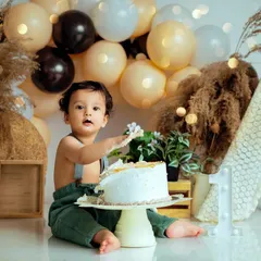 The aftermath of a successful cake smash. This little boy is enjoying his first taste of birthday cake in our popular bohemian-style studio set.