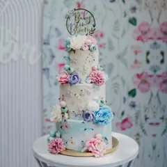This three-tier "Baby in Bloom" cake was designed to match the floral backdrop of the event. It features multiple flavors like Vanilla Caramel and Dark Chocolate Nutella, all finished in beautiful buttercream.