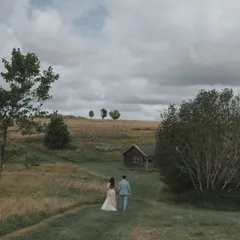 A wide, cinematic shot of the couple walking through the rolling hills of the English countryside. This image showcases the beautiful, rustic landscape of their destination wedding.