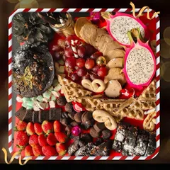 A festive dessert platter designed to dazzle. This beautiful charcuterie-style board features exotic dragon fruit, rich brownies, waffles, fresh strawberries, and an assortment of other sweet treats.