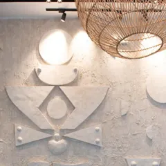 A close-up of a custom-designed, three-dimensional geometric art wall. The raw, textured concrete finish and abstract shapes create a powerful focal point.