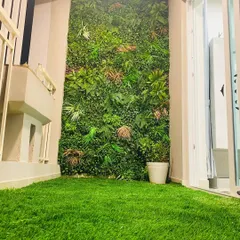 A cozy balcony setup featuring our soft-touch artificial grass and a vertical garden with varied leaf types and colors. This creates a natural, forest-like feel right outside your door.