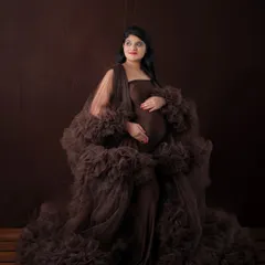 A dramatic low-key portrait featuring a voluminous brown tulle gown. The dark, moody lighting creates a sense of mystery and high fashion.